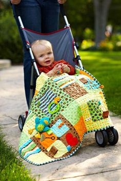 a baby sitting in a stroller with a blanket on it