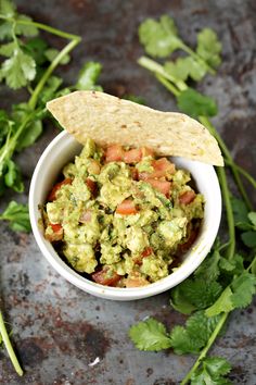 a bowl filled with guacamole and topped with a tortilla chip