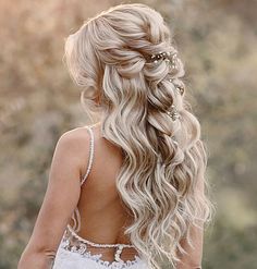 a woman with long blonde hair wearing a white dress and flower in her hair is looking back at the camera