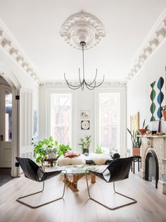 a living room filled with furniture and a fire place under a chandelier over a glass top table