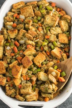 a casserole dish filled with stuffing, vegetables and croutons in it