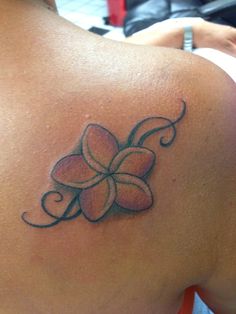 the back of a woman's shoulder with a flower tattoo on her left side