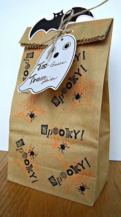 a brown paper bag decorated with black and orange spider webs, bats, and a ghost on it