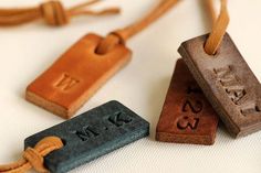 three wooden tags with initials on them are tied to a cord and placed next to each other