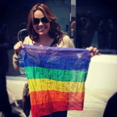 a woman holding up a rainbow colored shirt