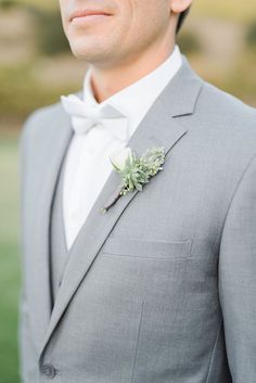 a man in a gray suit with a boutonniere and white flower on his lapel