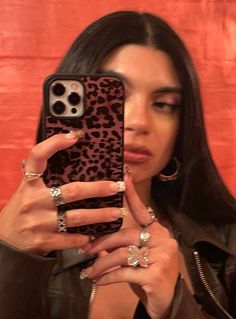 a woman taking a selfie with her cell phone in front of an orange wall