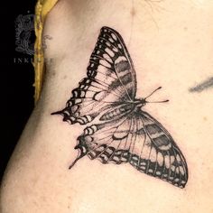 a black and white butterfly tattoo on the back of a woman's left shoulder