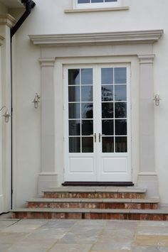 a white door with two windows and steps leading up to it