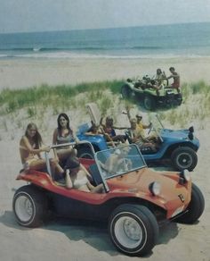 people are riding in an old style dune buggy on the beach while others watch