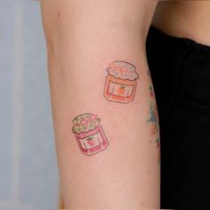 a woman's arm with tattoos on it and two cakes in the middle one