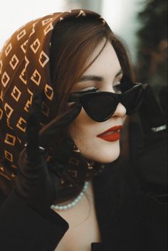 a woman wearing sunglasses and a scarf on her head