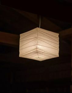 a white light hanging from the ceiling in a dark room