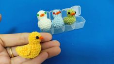 three small crocheted birds sitting next to each other in plastic containers on a blue surface