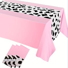 a pink table cloth with black and white spots on it, along with matching napkins