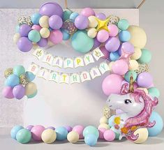 a birthday party with balloons and unicorns on the wall next to it is decorated in pastel colors