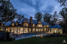 a large house with a swimming pool in the front yard at night, surrounded by trees and grass