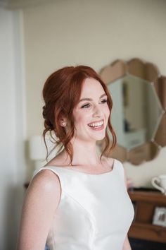 a woman in a white dress smiles at the camera while standing next to a mirror