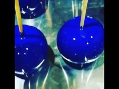 two blue apples with yellow sticks sticking out of them sitting on top of a table