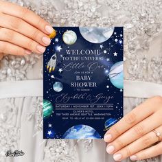 a woman in a white dress holding up a space themed baby shower card that says, welcome to the universe