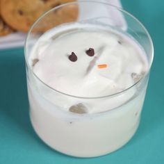 a glass filled with milk and cookies on top of a blue tablecloth next to a plate full of cookies