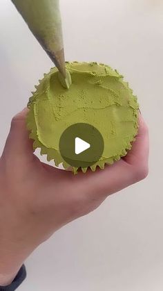 a person holding a green cupcake in their hand with a video playing on it