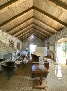 a living room filled with furniture and a fire place next to a stone wall covered in windows