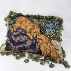 an embroidered pillow with two dogs and flowers on the front, one is brown and the other is green