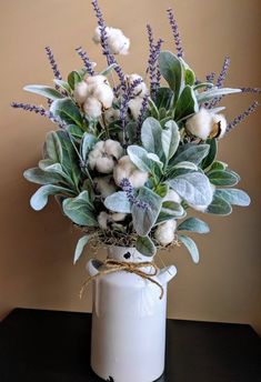 a white vase filled with flowers and greenery