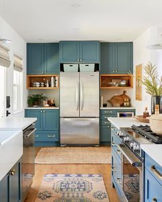 a kitchen with blue cabinets and white counter tops, an area rug on the floor