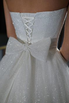 the back of a white wedding dress with sequins on it's skirt