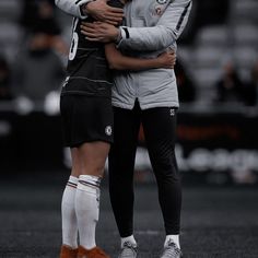 two soccer players hugging each other on the field