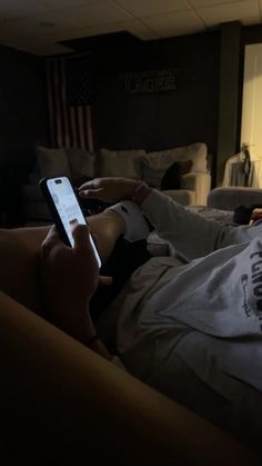 a person laying in bed holding a cell phone