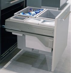 an open drawer in the middle of a kitchen with two bottles and cans inside it