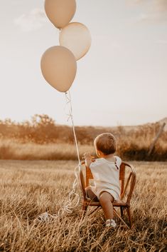 a little boy sitting in a chair with balloons