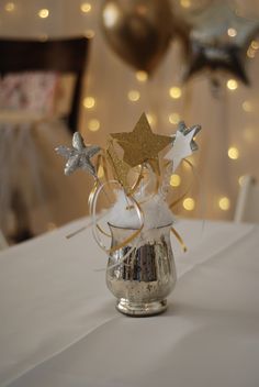 a small vase filled with white and gold stars on top of a table covered in confetti