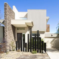 a modern house with stone walls and wooden steps leading up to the front door area