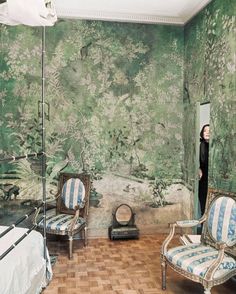 an old fashioned bedroom with green wallpaper and white bed in the corner, two chairs on either side