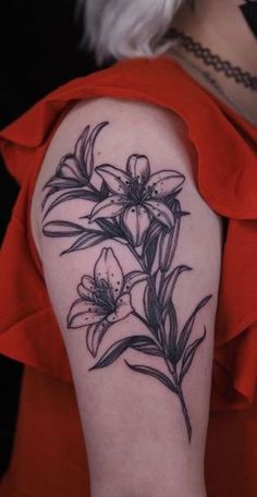 a woman's arm with flowers and leaves on the back of her left arm