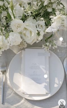 a table setting with white flowers and silverware