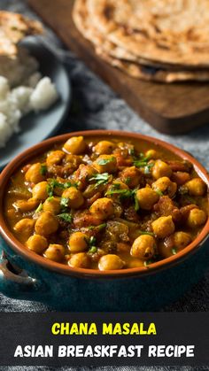 a blue bowl filled with chickpeas next to rice and pita bread on a table