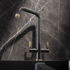 a black and gold sink faucet in a bathroom with marble wallpaper, brass accents