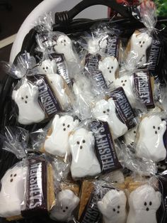 a basket full of halloween cookies with white ghost faces on them, wrapped in cellophane