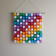 a multicolored wall hanging made out of cubes and toothpicks on a white wall