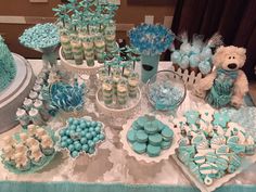 a table topped with lots of blue and white desserts next to a teddy bear