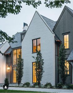 a large white house with two story windows and trees in the front yard at dusk