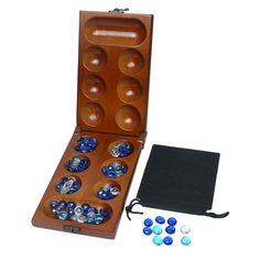 an open wooden box filled with blue and white marbles next to a black case