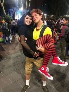 a man and woman are posing for a photo in front of a crowd at night