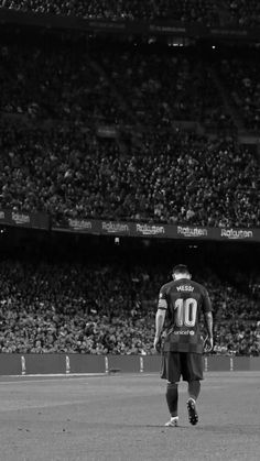 a man standing on top of a field next to a soccer ball in front of a crowd