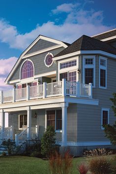 a large gray house with white balconies on the second floor and two story windows